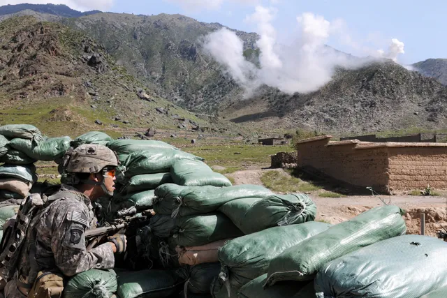 U.S. Army soldier at a Kunar checkpoint as 120 mm white phosphorus mortar rounds hit a nearby ridgeline
