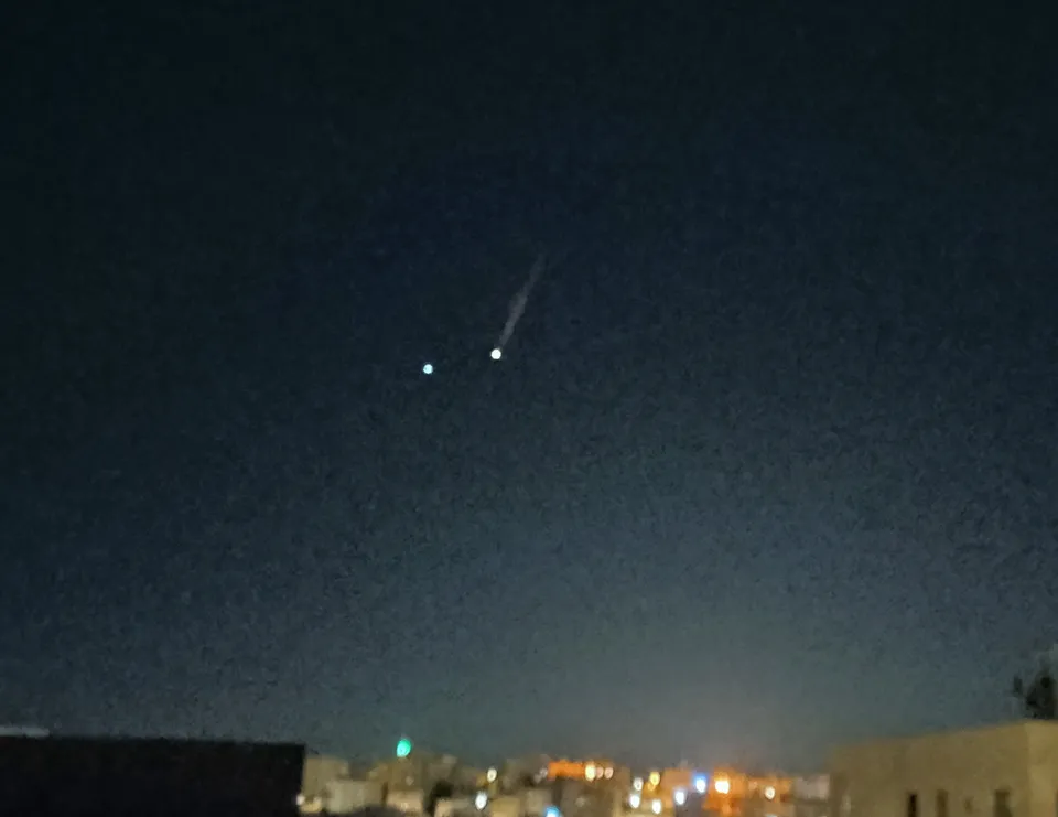 Two missiles visible in the night sky over western Amman during Iranian strikes toward Israel