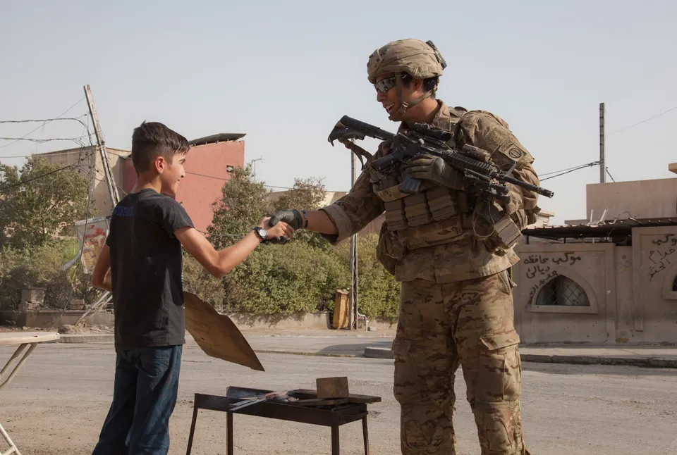 U.S. Army paratrooper shaking hands with a child in Mosul during 2014 Operation Inherent Resolve in July 2017